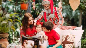 Una familia con una figura de Papá Noel, una máquina de coser y un adorno con forma de corazón en un jardín.