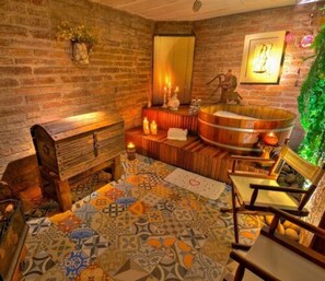 A spa room with a wooden bench, a large bathtub, and a patterned floor.