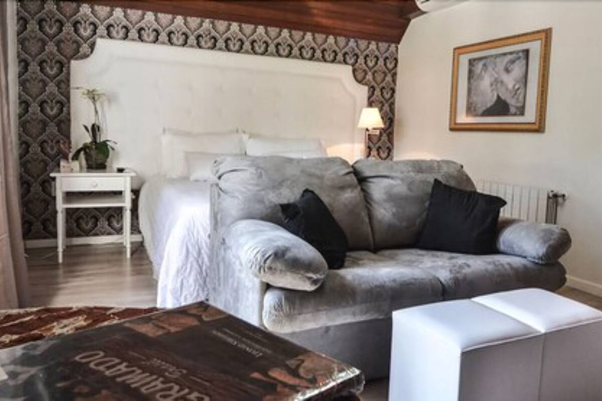 A living room with a grey sofa, a small white side table, a lamp, and a framed picture on the wall.
