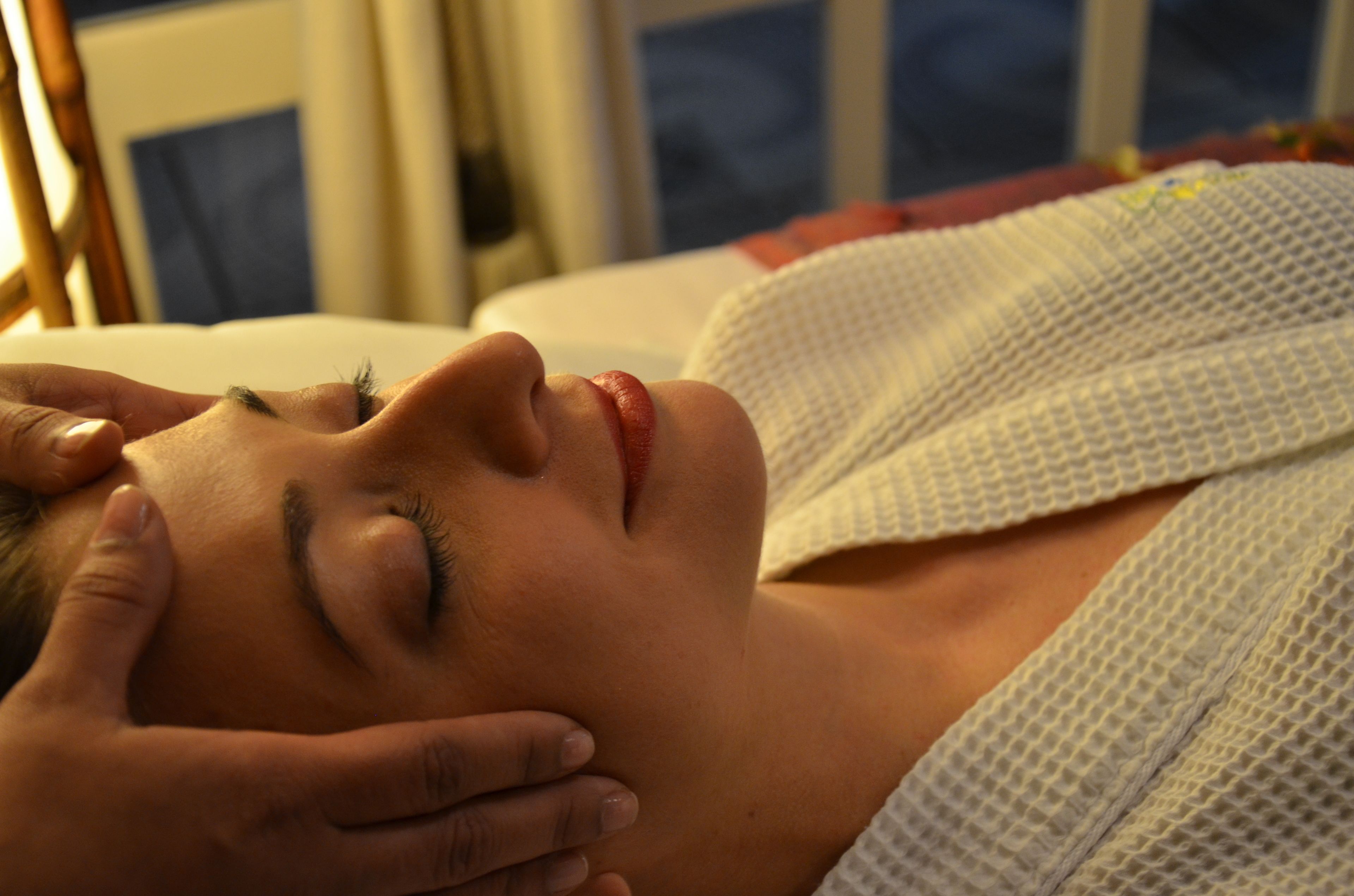 A person lying down with a hand on their forehead, possibly in a relaxed or resting position.