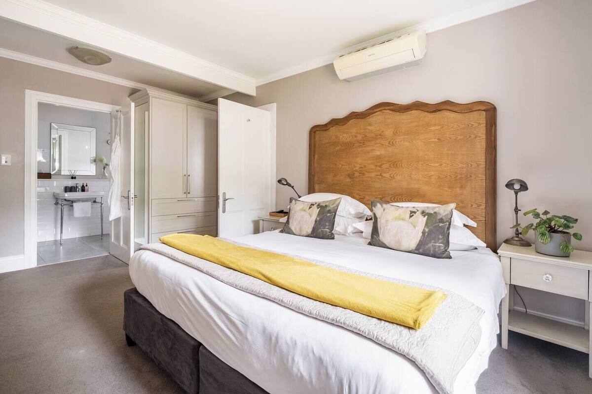 Een slaapkamer met een bed, nachtkastjes, een spiegel, een kledingkast en een airconditioning.