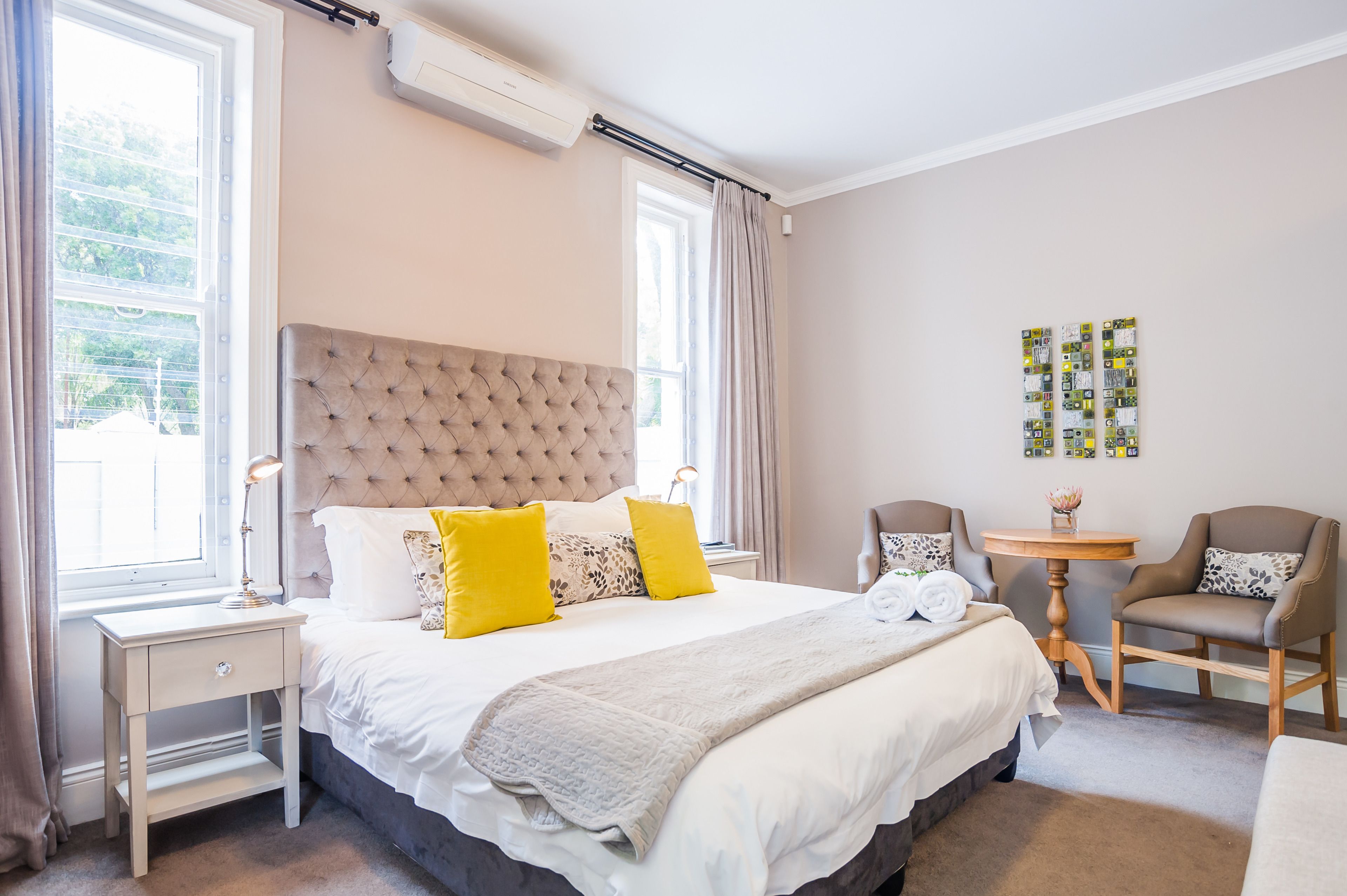 Une chambre d’hôtel avec un grand lit, deux tables de chevet, une petite table ronde et deux chaises.