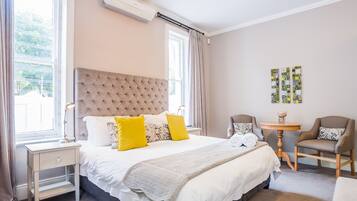 Une chambre d’hôtel avec un grand lit, deux tables de chevet, une petite table ronde et deux chaises.