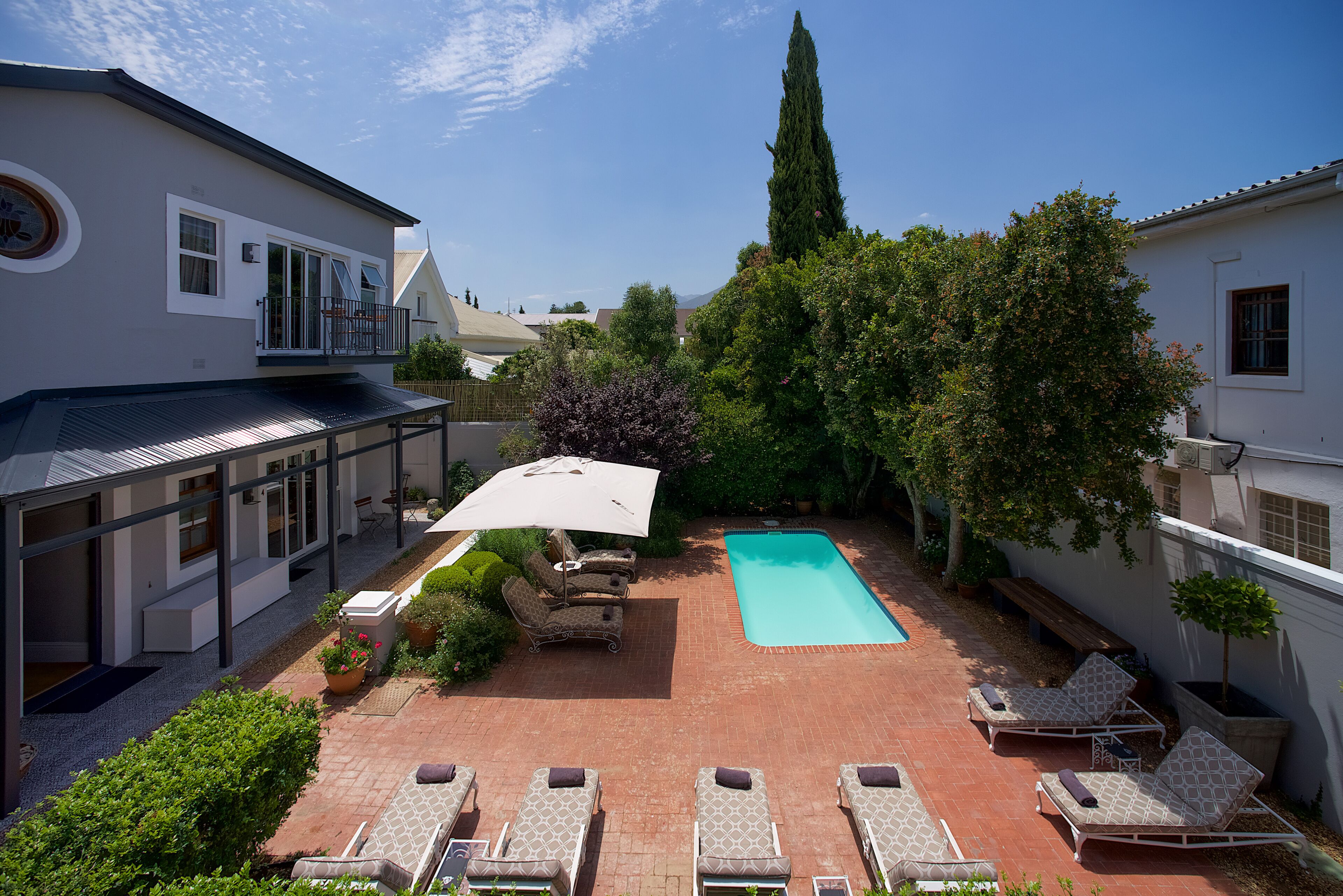 Un patio con piscina, sillas de descanso y plantas en macetas.
