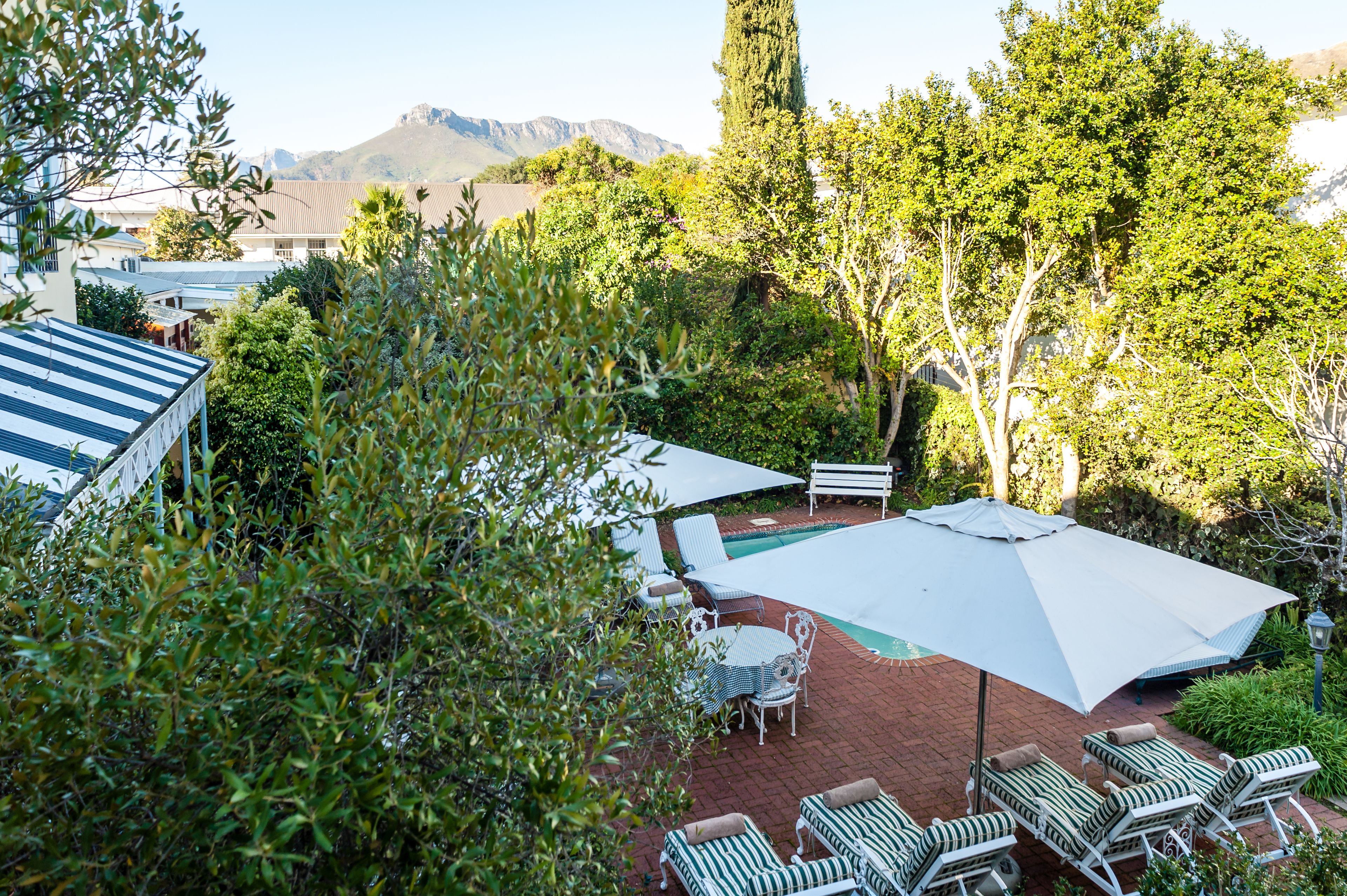 A patio area with a pool, lounge chairs, and a table with umbrellas.