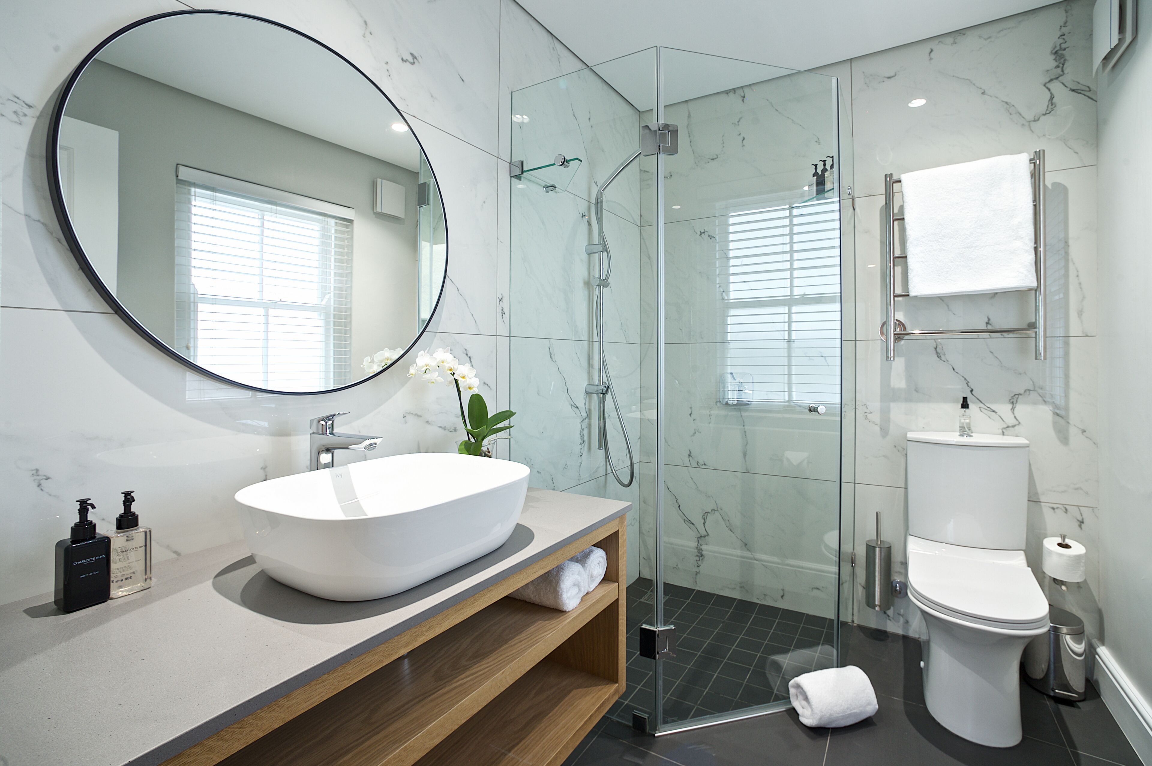 A modern bathroom with a large oval sink, a glass-enclosed shower, and a toilet.