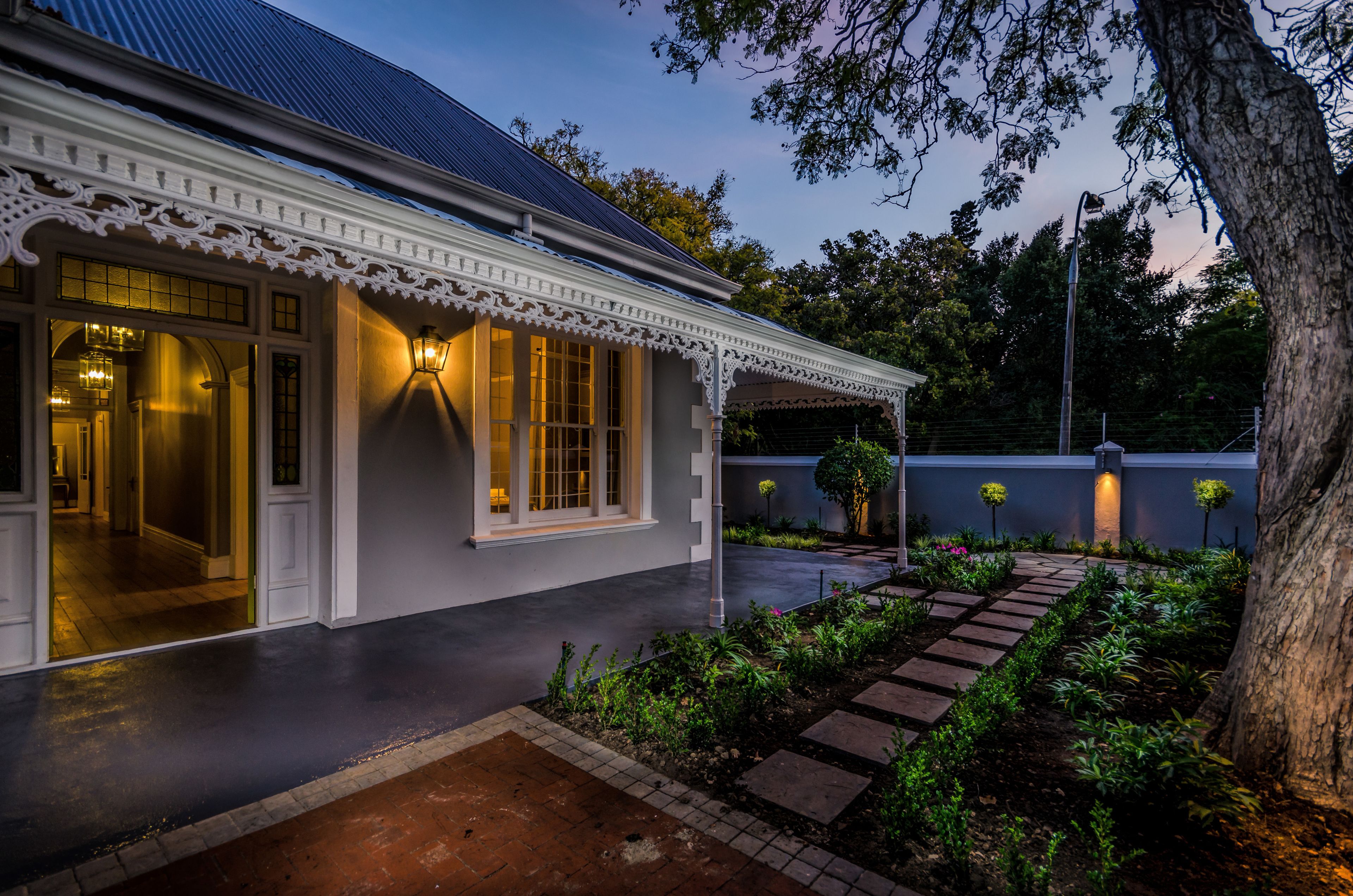 A traditional house with a well-maintained garden, a paved walkway, and a visible entrance.