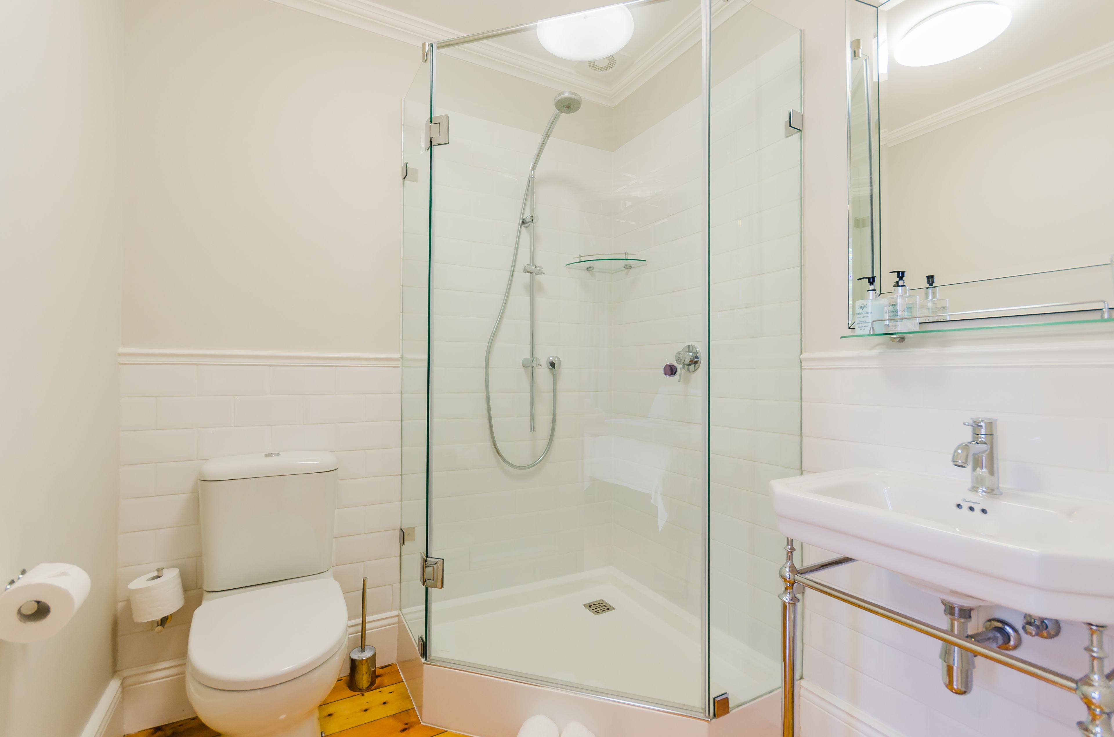 A modern bathroom with a glass-enclosed shower, a white toilet, and a sink with a mirror above it.