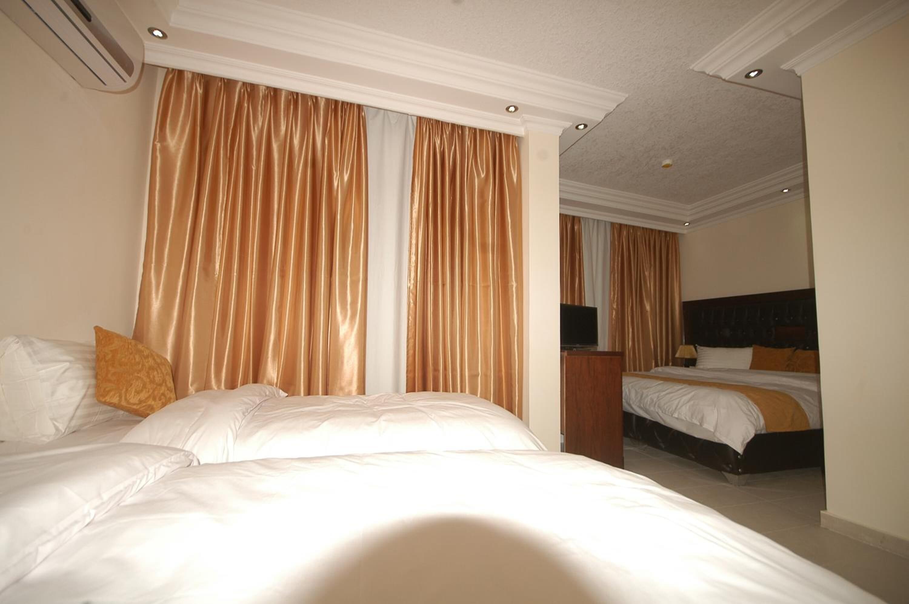 A hotel room with two beds, a television, and a mirror.