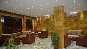 A lobby with marble flooring, brown sofas, and a large window. - Sharah Mountains Hotel (Wadi Musa)
