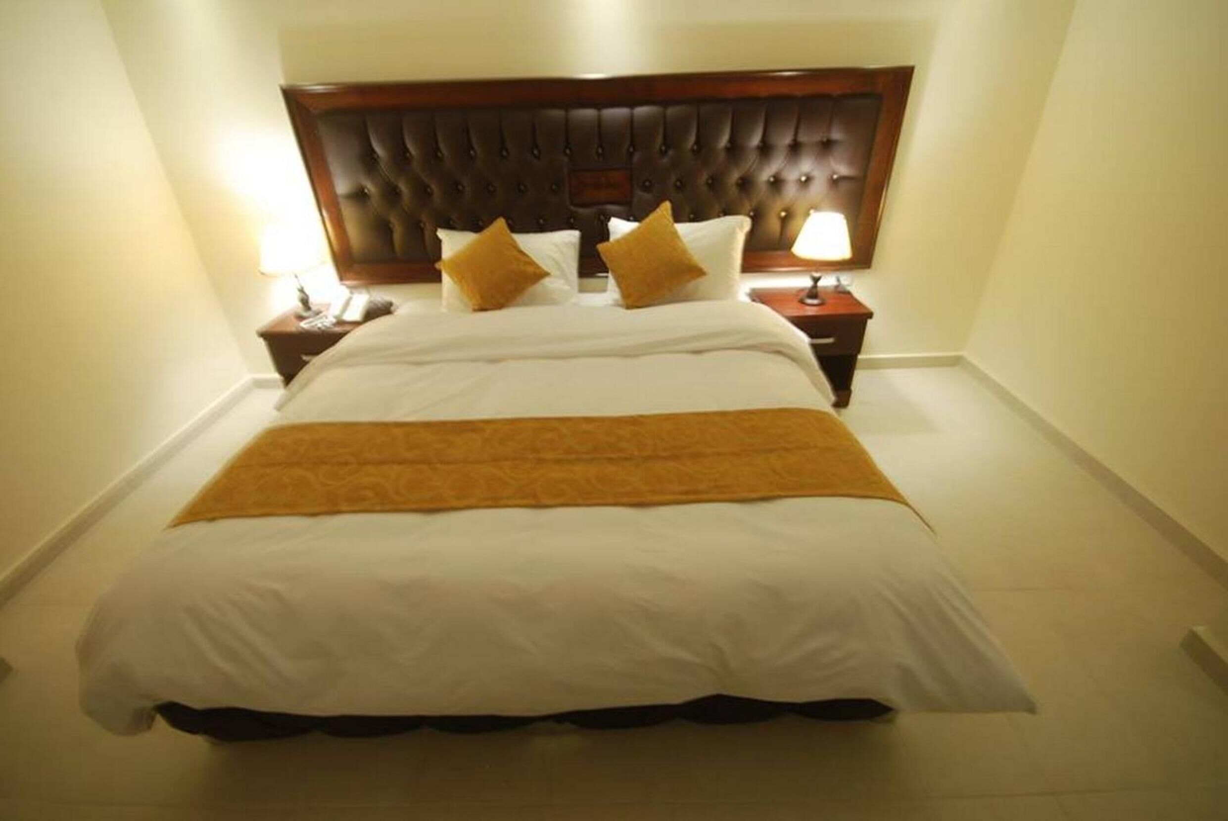 Una habitación de hotel con una cama grande, dos mesitas de noche y un cabecero de madera.