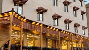 A multi-story hotel with a traditional architectural style, featuring a covered outdoor seating area with wooden railings and tables. - Sharah Mountains Hotel (Wadi Musa)
