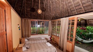 A room with two beds, a hammock, and a view of greenery. - Huasquila Amazon Lodge (Cotundo)