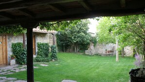 Een binnentuin met een kiezelpad, een houten pergola en een stenen muur met een deur.
