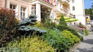 A hotel with a balcony, a staircase, and a variety of plants. - Venus (Karlovy Vary)