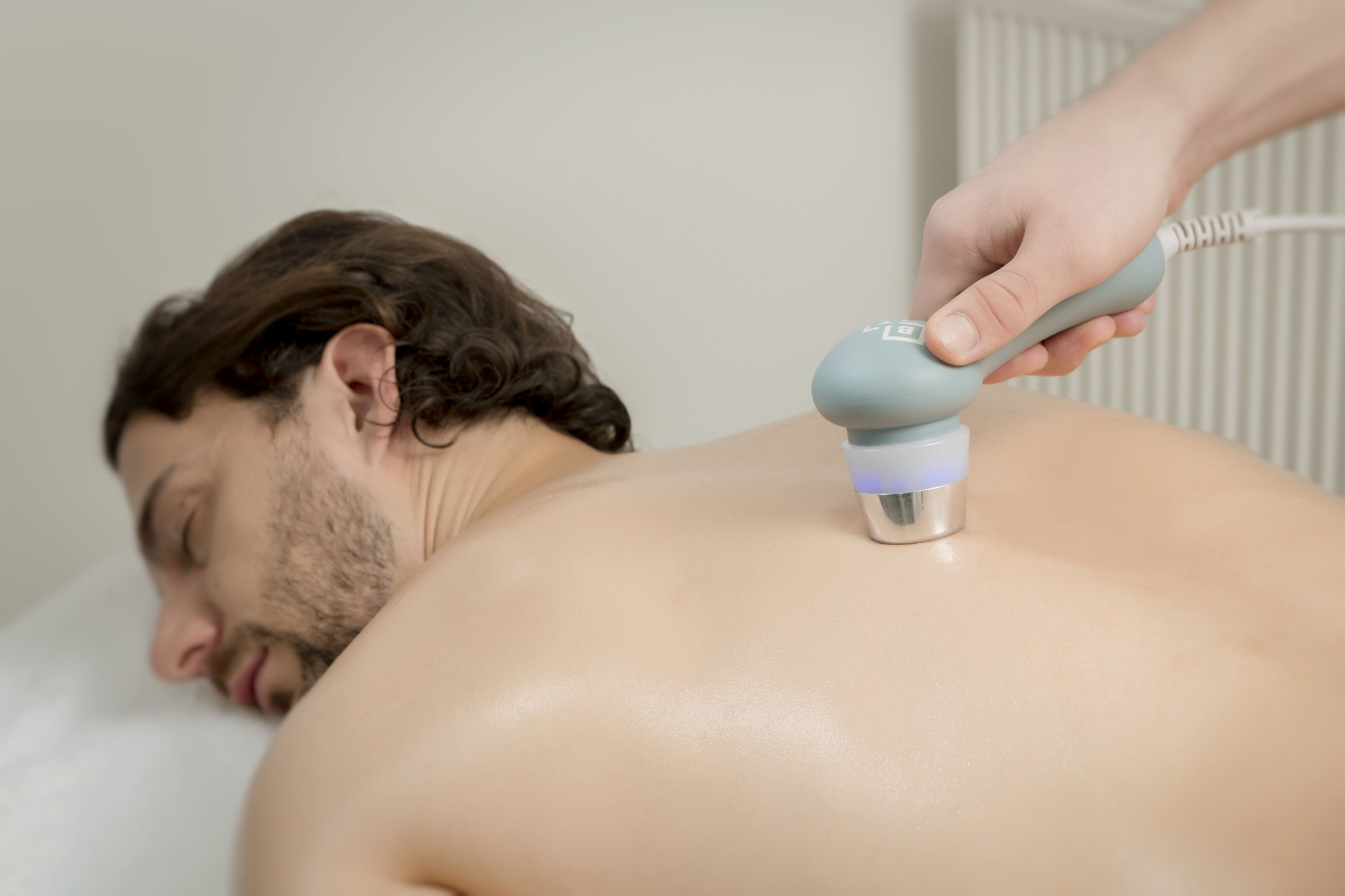 A person receiving a treatment on their back with a handheld device.