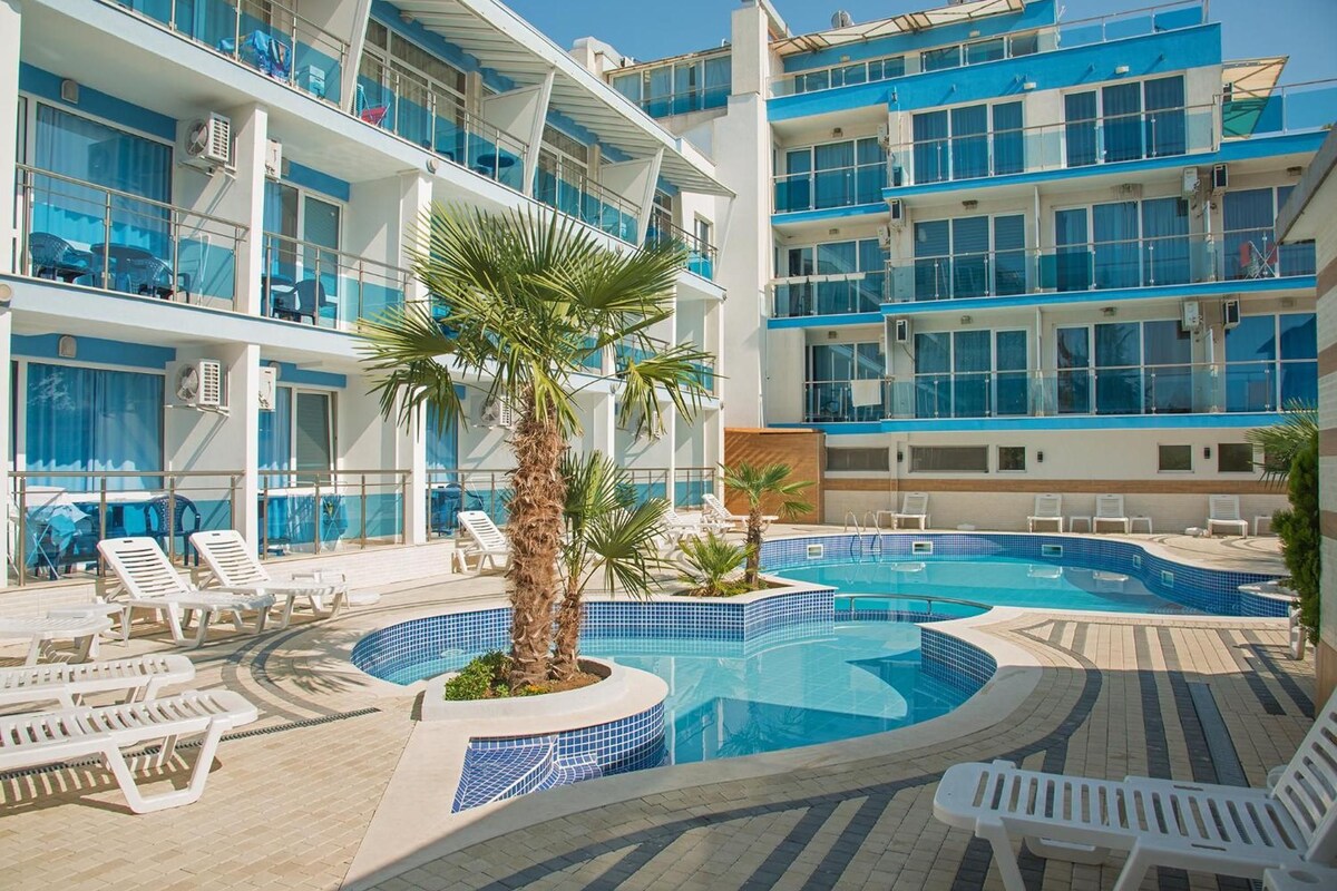 A pool area with lounge chairs and a palm tree.