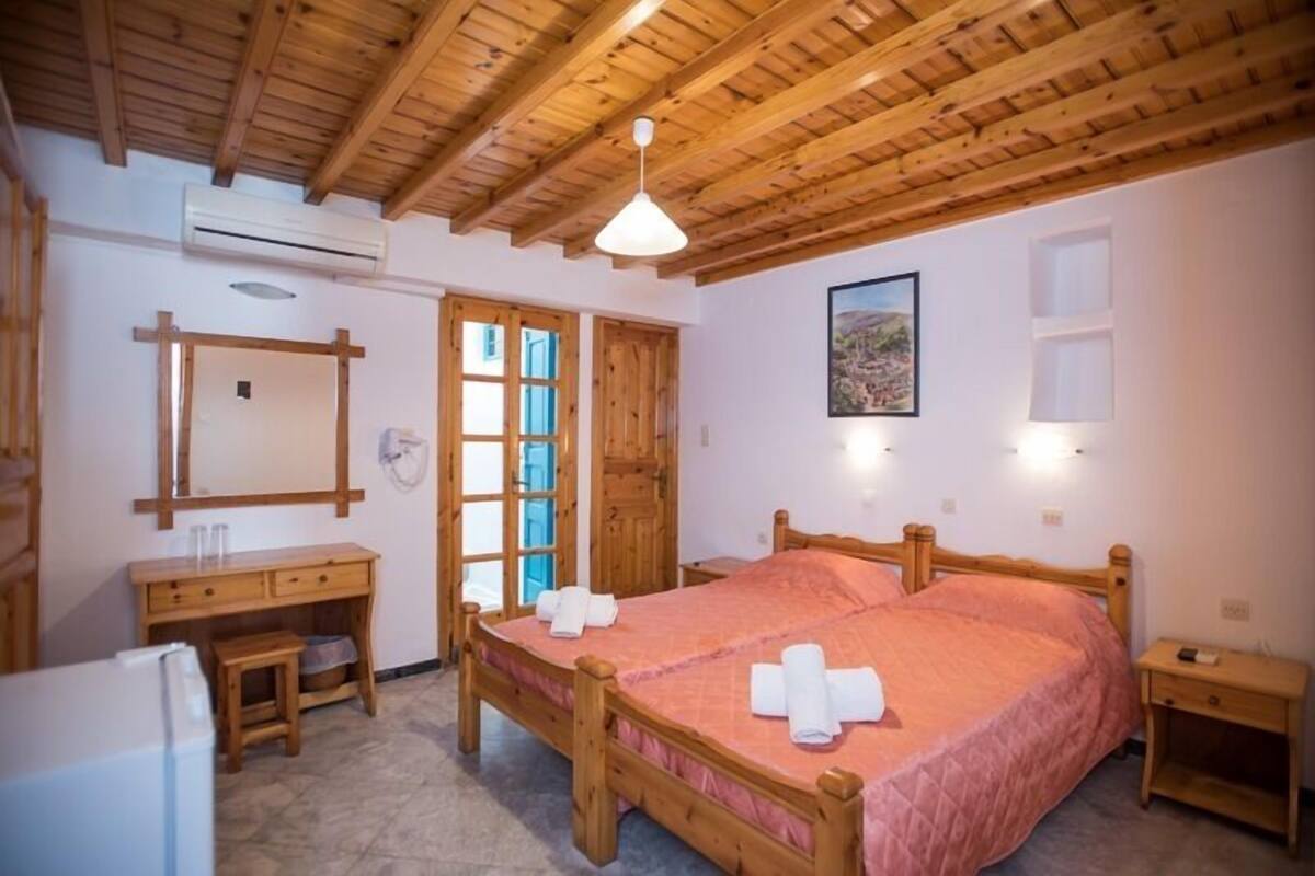 Un dormitorio con una cama de madera, un aparador de madera, una mesita pequeña y un espejo.