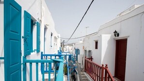 Una calle estrecha con edificios blancos, puertas azules y barandillas rojas.