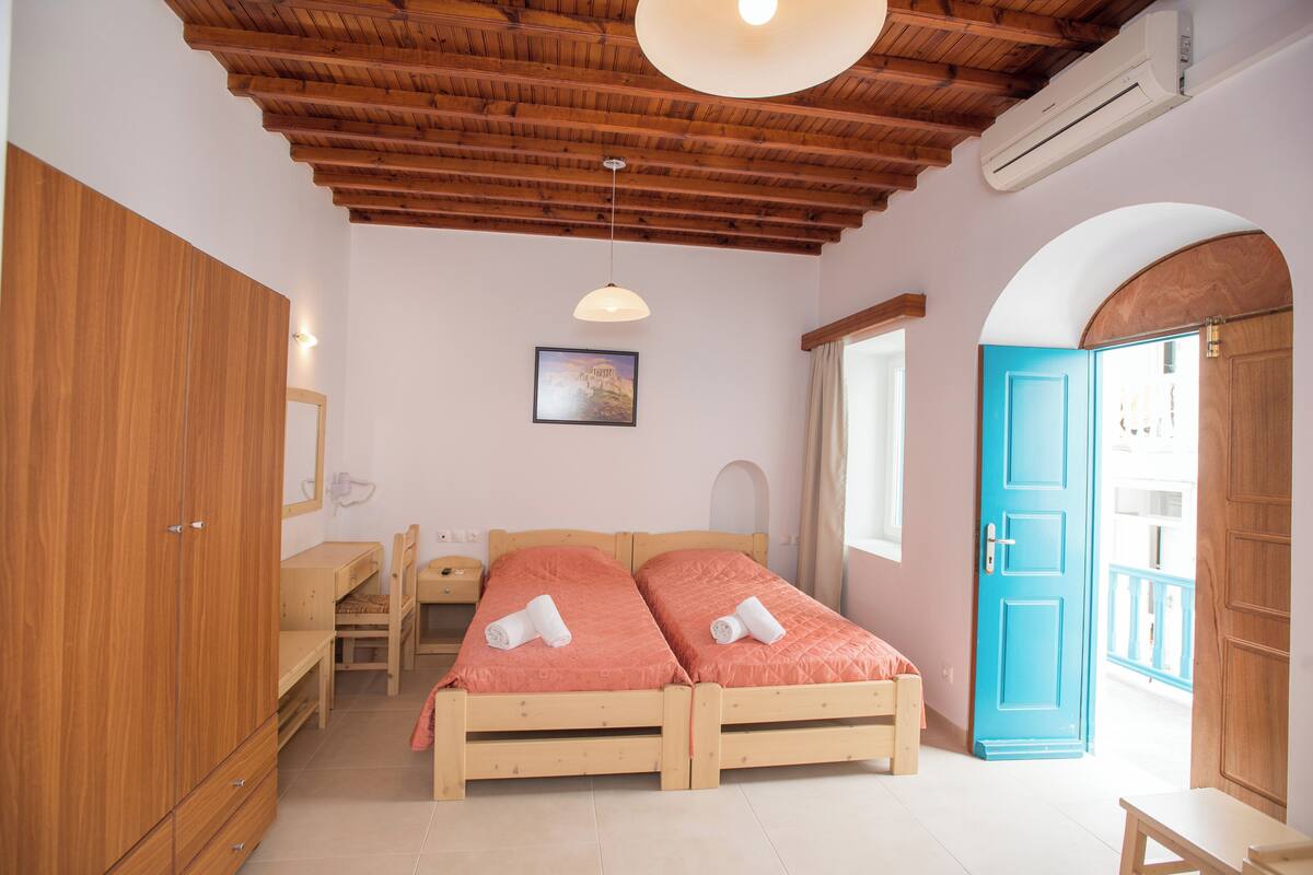 Un dormitorio con una cama de madera, un escritorio, una silla, un armario y un arco en el acceso.