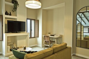 Ein modernes Wohnzimmer mit Fernseher, Esstisch, Sofa und Arbeitsplatz.
