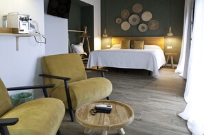 Ein Hotelzimmer mit einem Bett, zwei Sesseln, einer Kaffeemaschine und einem kleinen Tisch mit einer Fernbedienung.