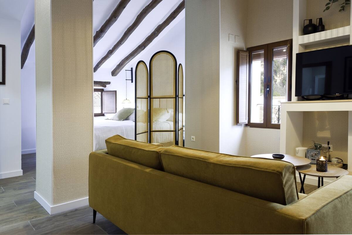 A modern living room with a sofa, a television, and a dining area.