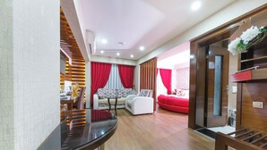 A modern living room with a sofa, a dining table, and a red accent wall. - Marlight Boutique Hotel - Boutique Class (Izmir)