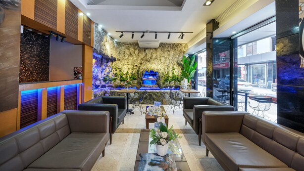 A lobby with leather sofas, a reception desk, and a decorative wall with a water feature. - Marlight Boutique Hotel - Boutique Class (Izmir)