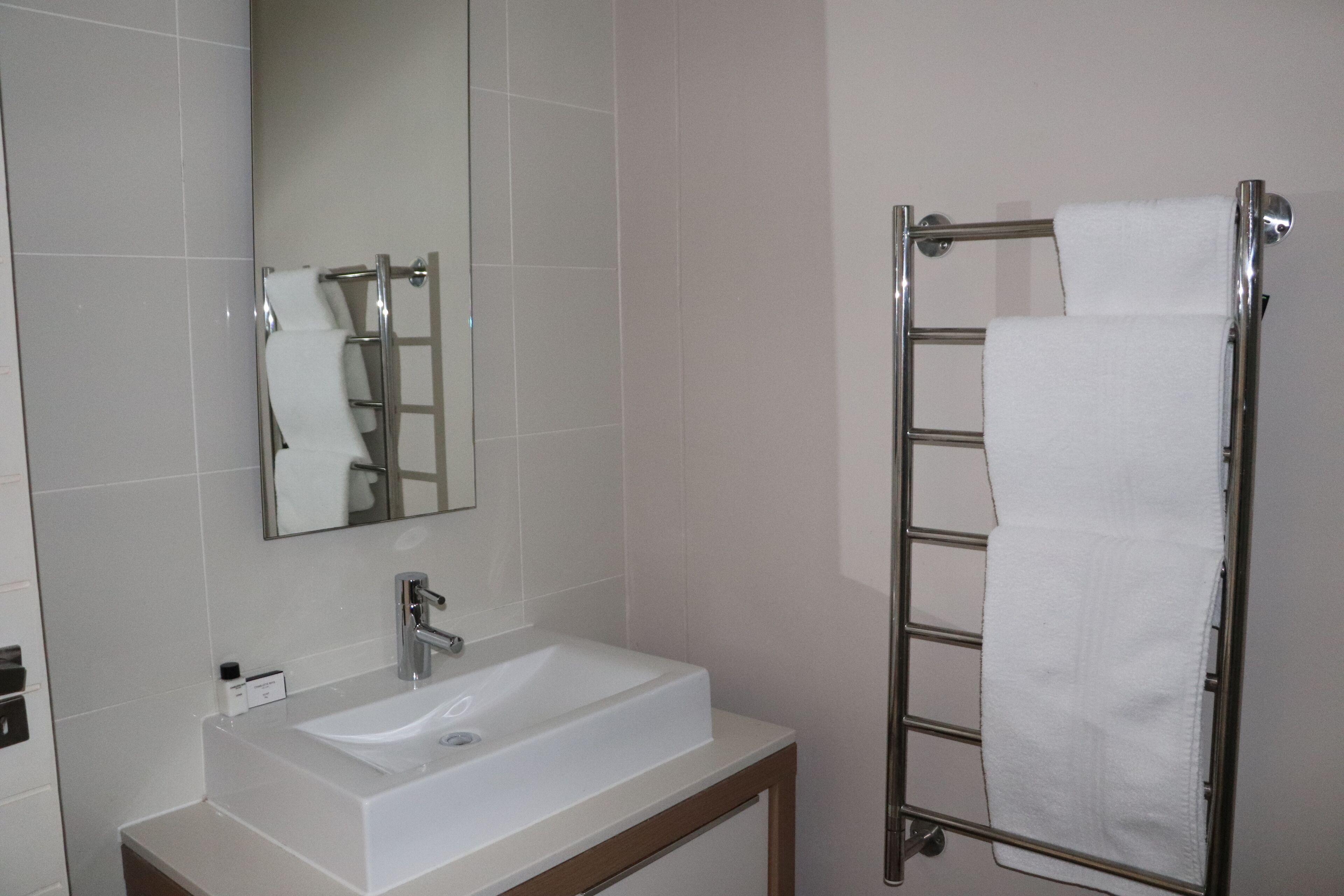 A bathroom with a white sink, a mirror, and a towel rack.