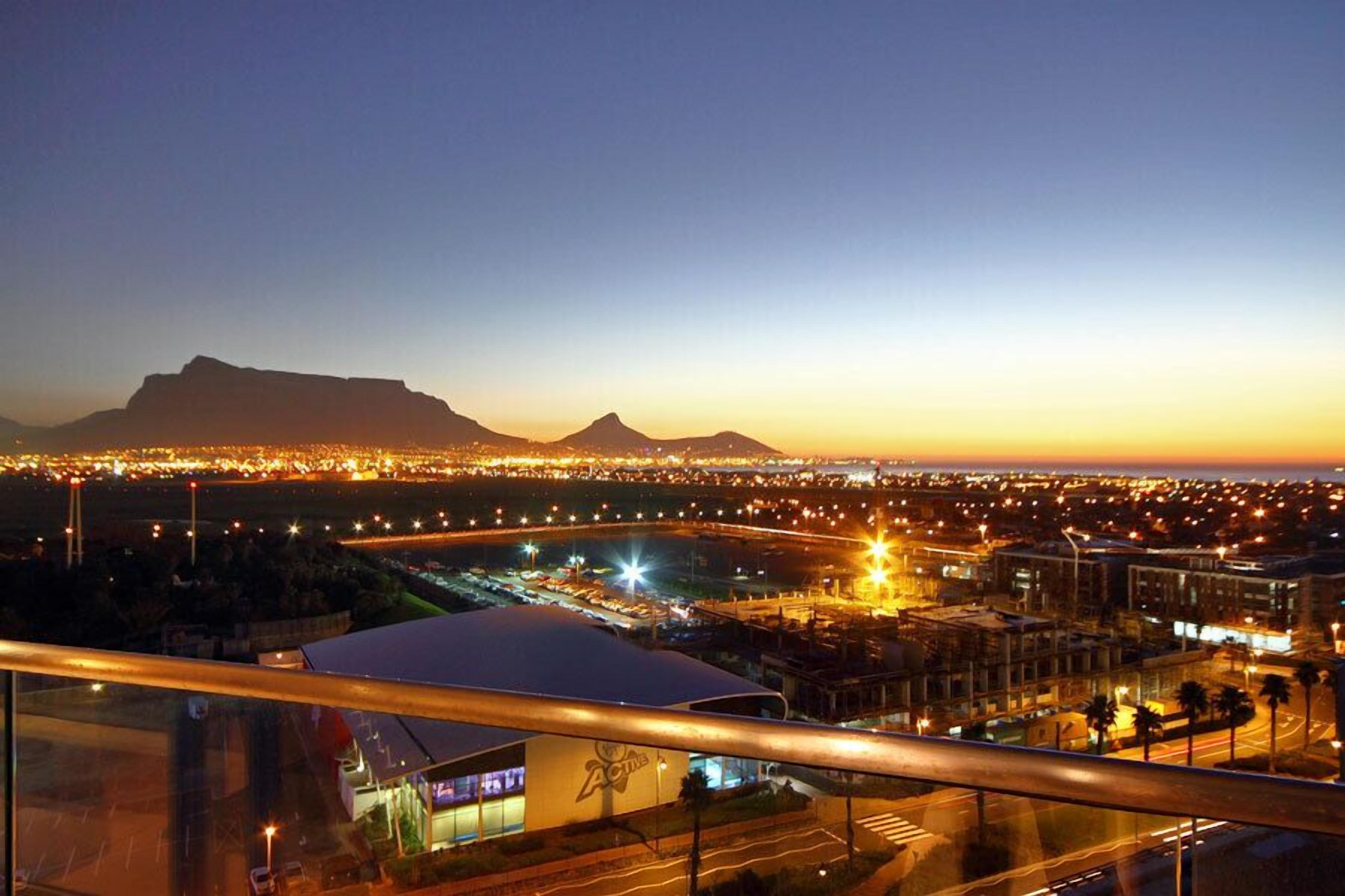 A cityscape at dusk with a prominent mountain in the background.