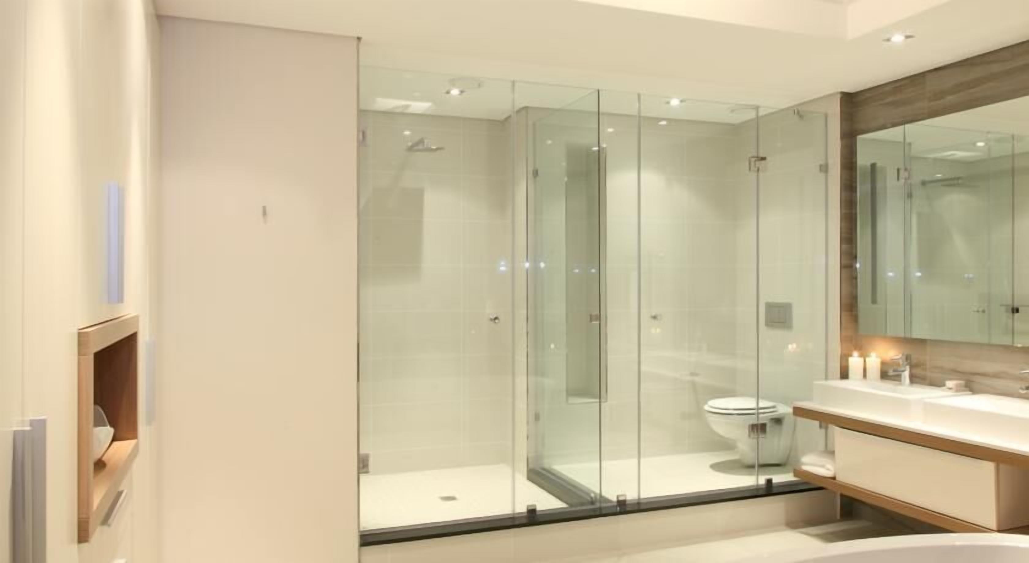 Een moderne badkamer met een douchecabine van glas, een toilet en een wastafel met spiegel.