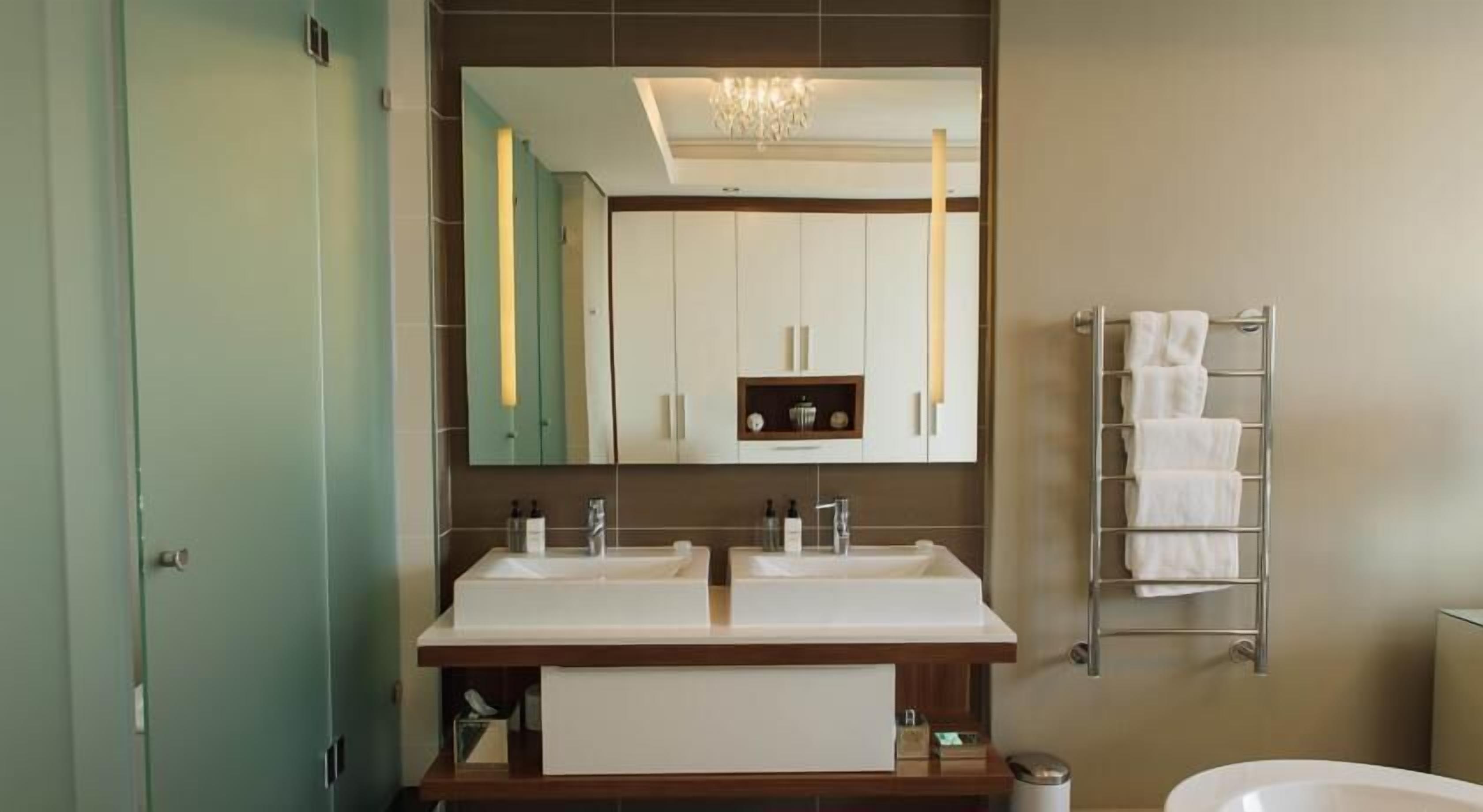 A bathroom with two sinks, a large mirror, and a towel rack.