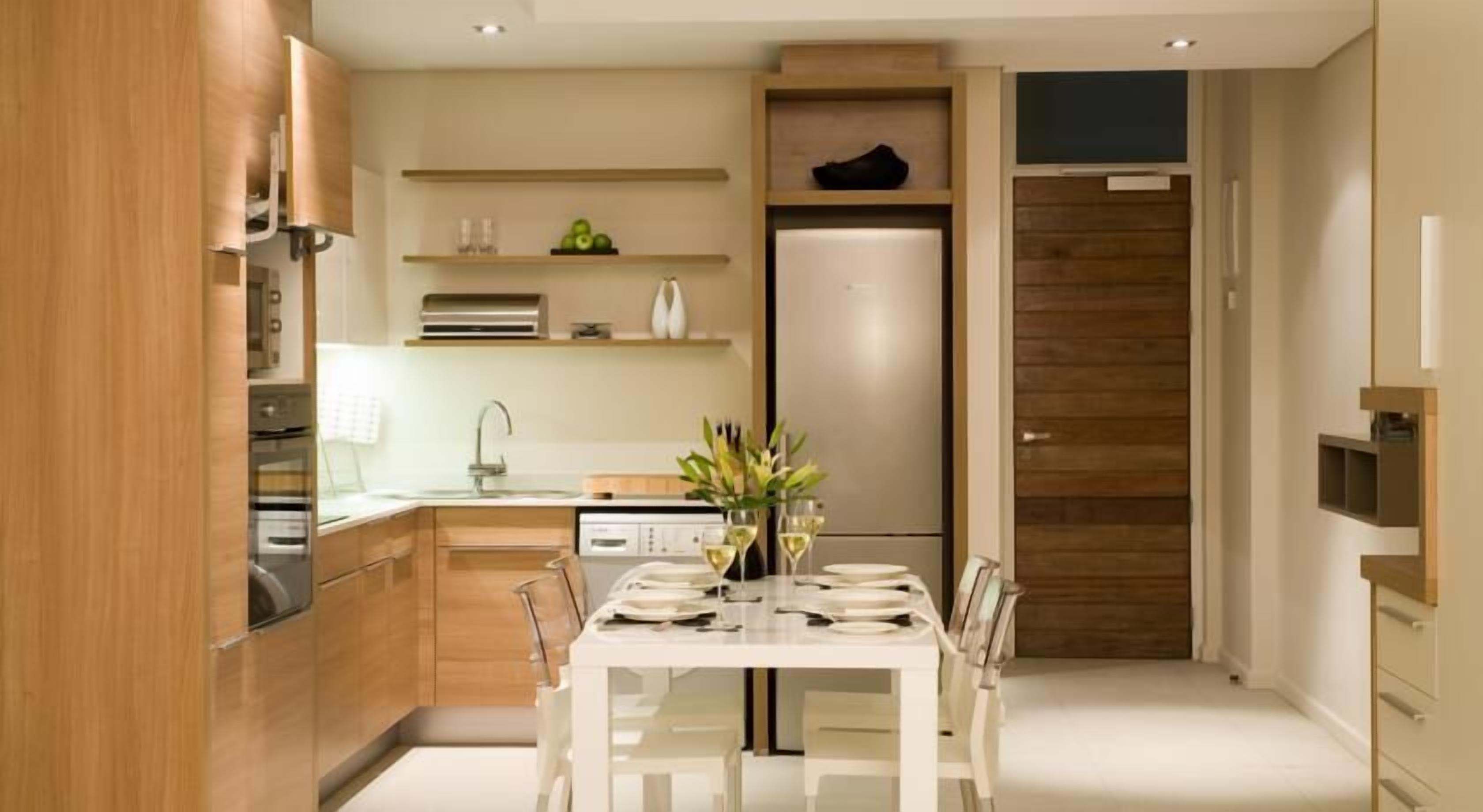 A modern kitchen with wooden cabinets, a built-in oven, and a dining area with a table set for two.