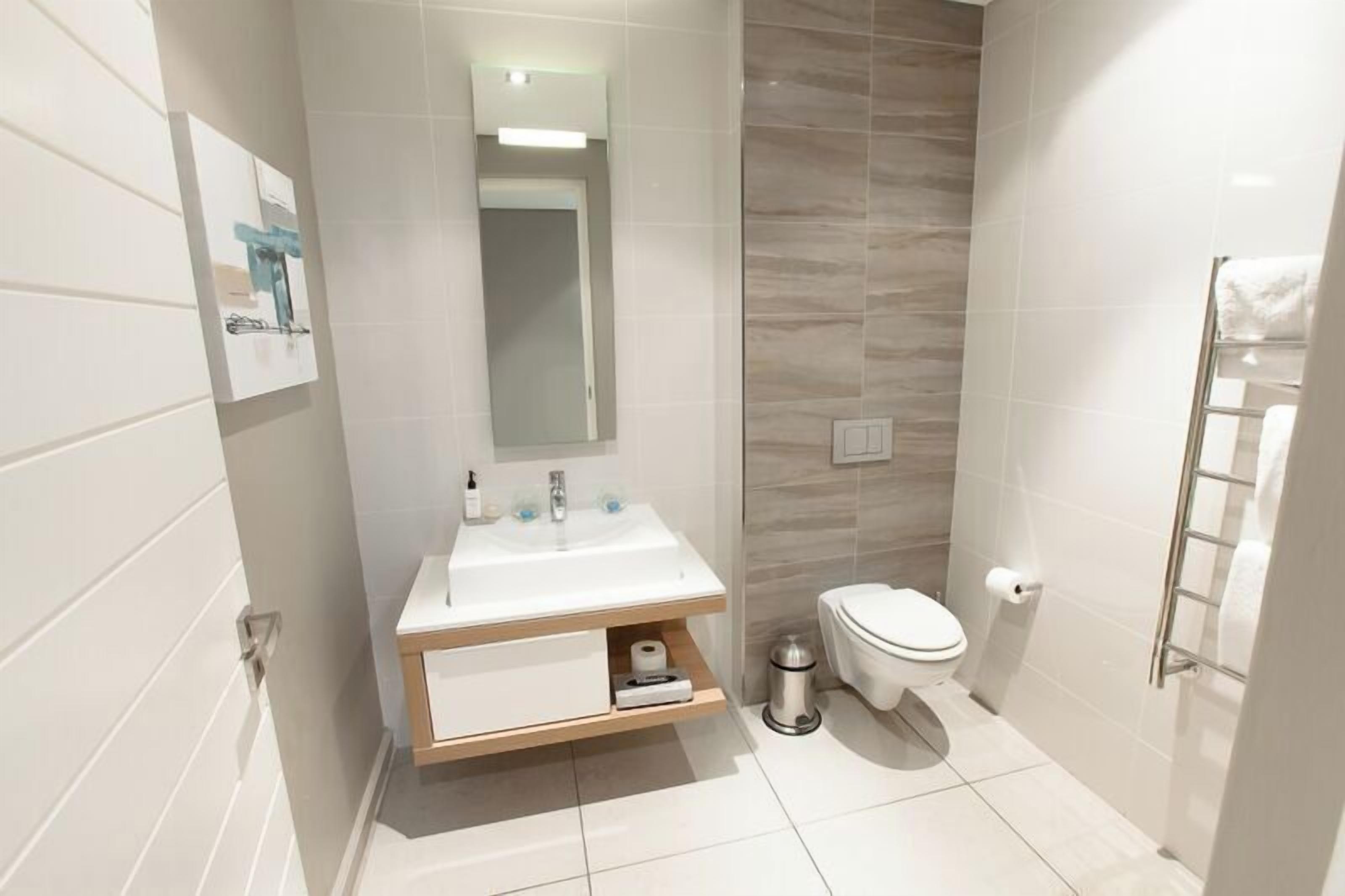 A modern bathroom with a white sink, mirror, and toilet.