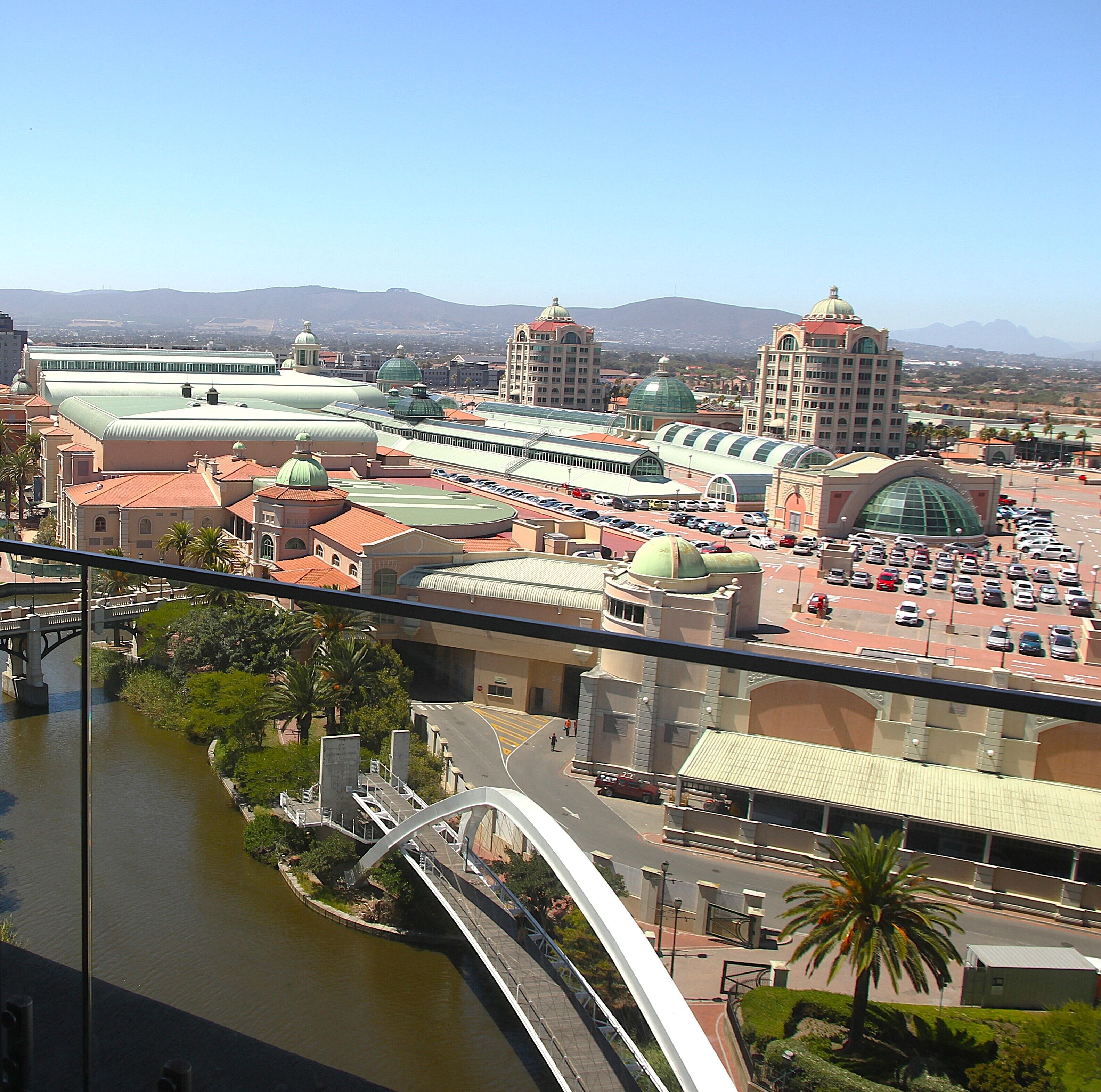 A cityscape with a prominent train station, a bridge over a river, and a mountain range in the background.