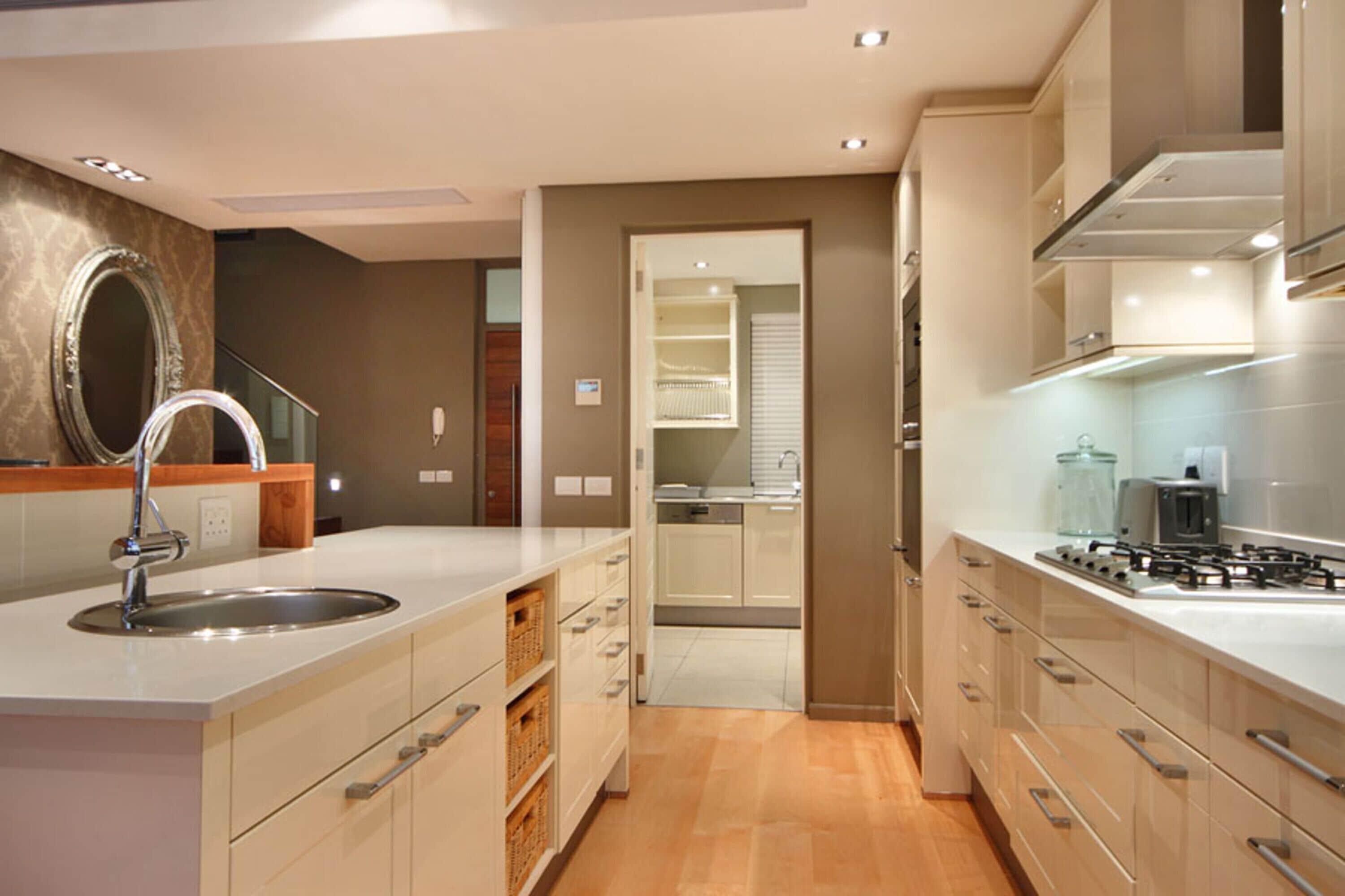 A modern kitchen with a central island, stainless steel sink, and built-in appliances.