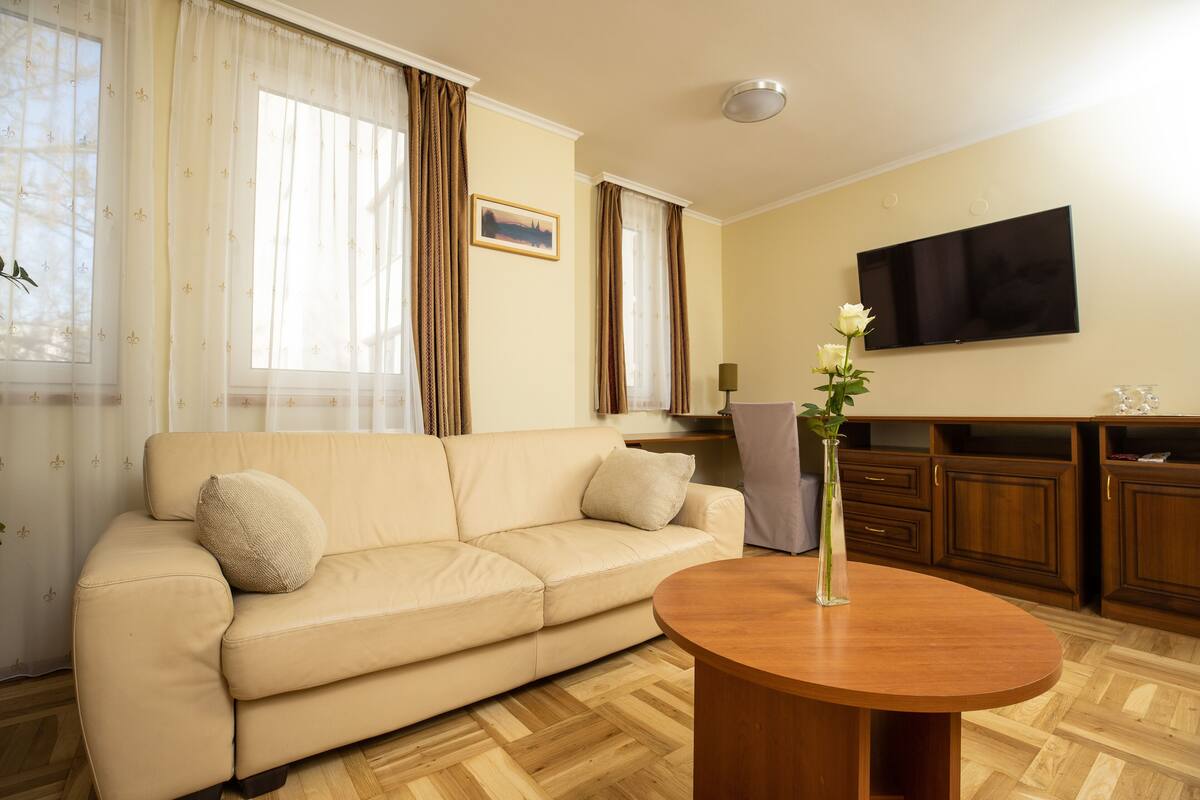 A living room with a beige sofa, a wooden coffee table, a flat-screen TV, and a wooden cabinet.