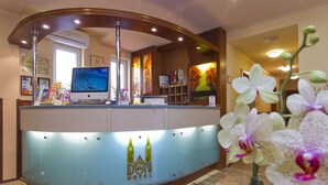 A hotel reception desk with a computer monitor, framed artwork, and a logo.