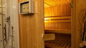 A sauna with wooden walls and a glass door, a control panel, and a towel rack.
