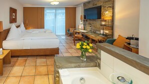 Una habitación de hotel con cama, escritorio, televisor y baño con bañera y ducha.