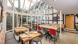 Un restaurante con techos altos, ventanas amplias y diferentes opciones de asientos, incluyendo mesas y cabinas.