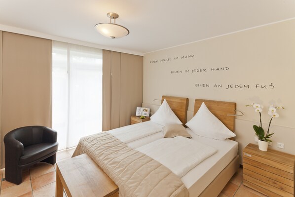 A neatly arranged bedroom with a bed, bedside tables, a chair, and a wall with text.