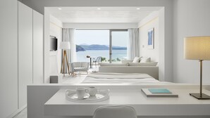 A modern hotel room with a large window offering a sea view, a cozy seating area, and a minimalist decor. - Lichnos Beach Hotel & Suites (Parga)