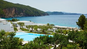 A resort with a swimming pool, lounge areas, and a view of the sea and mountains. - Lichnos Beach Hotel & Suites (Parga)