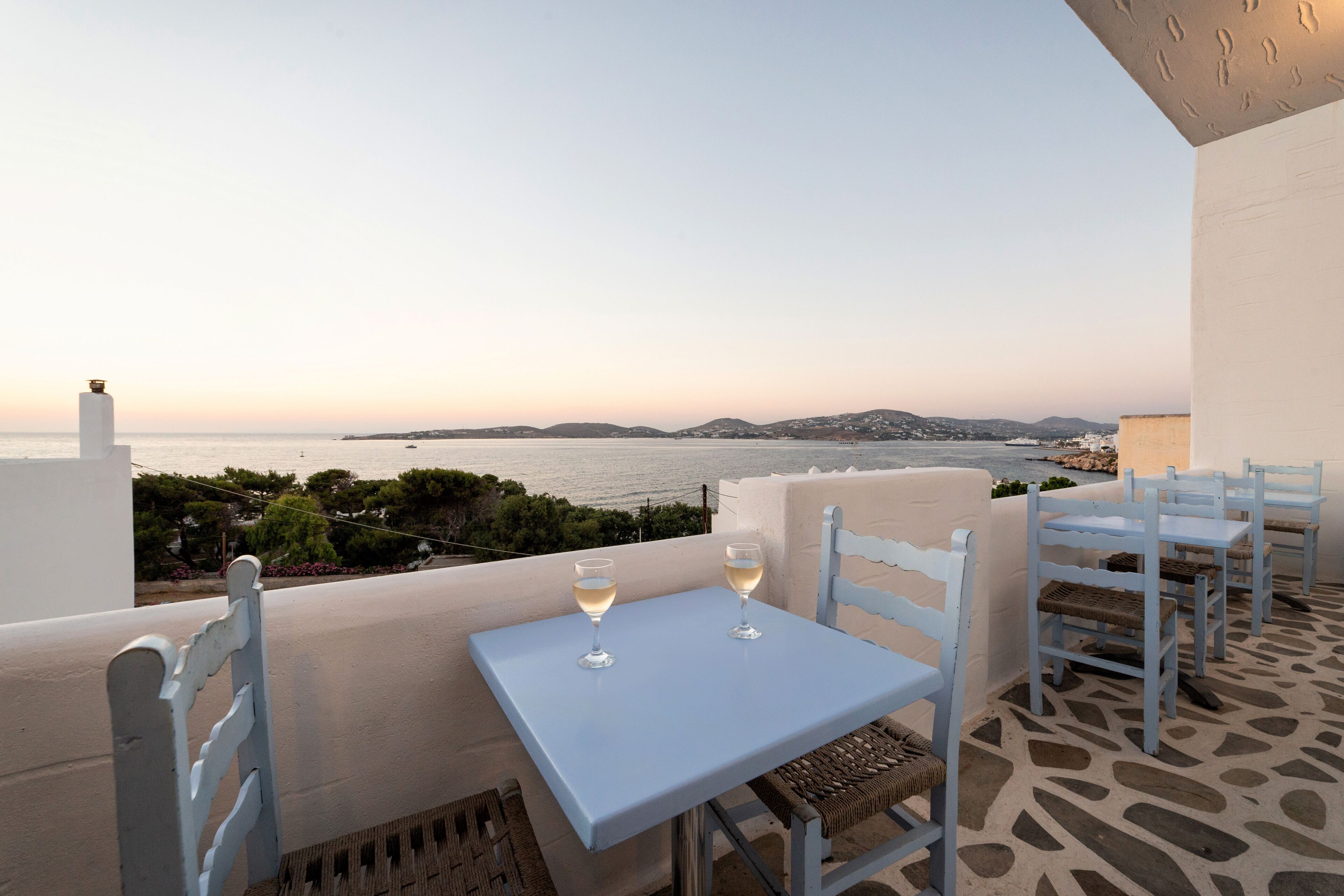 Une terrasse avec une table et des chaises blanches, offrant une vue sur la côte.