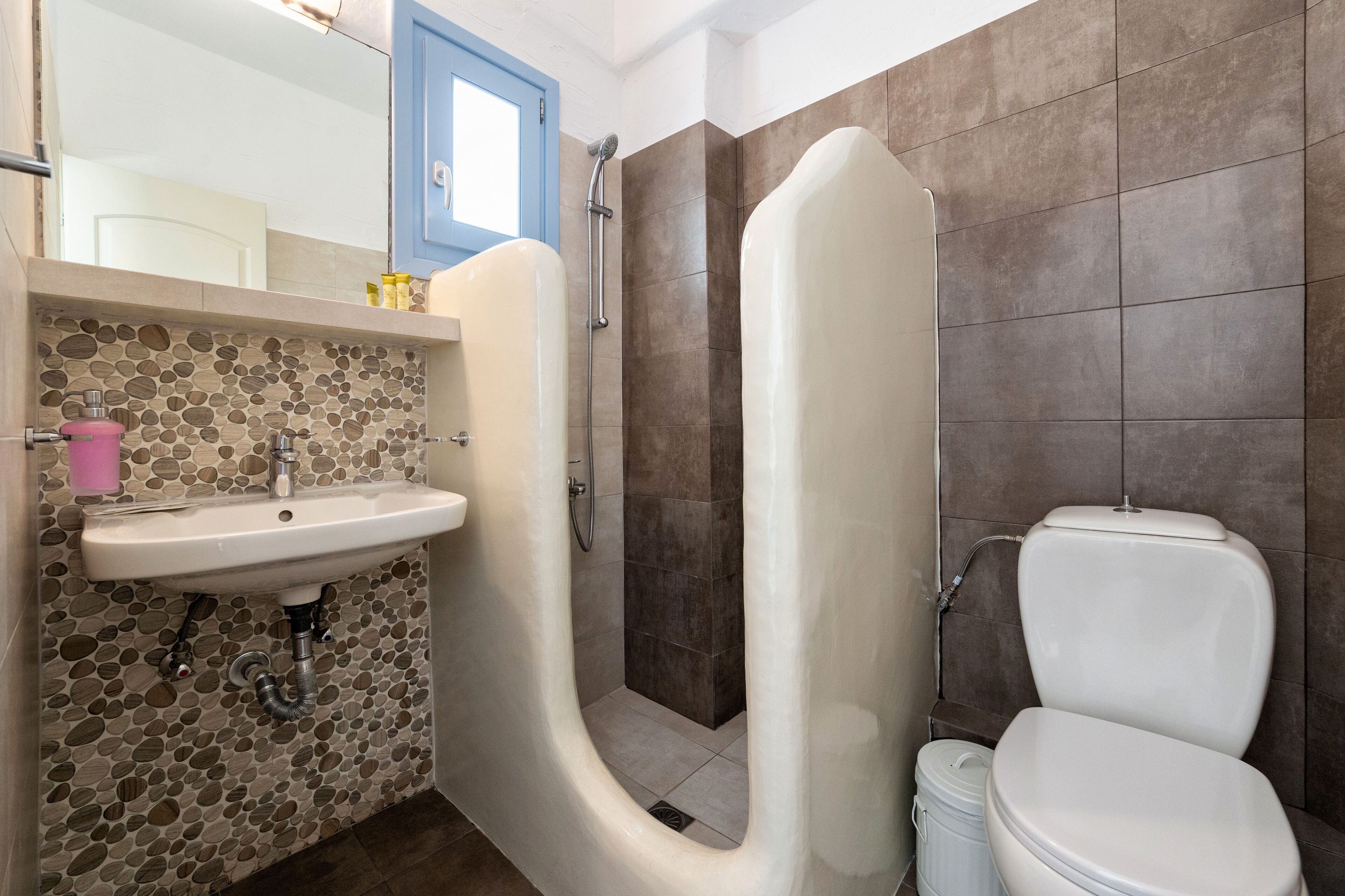 A bathroom with a white sink, a shower, and a toilet.
