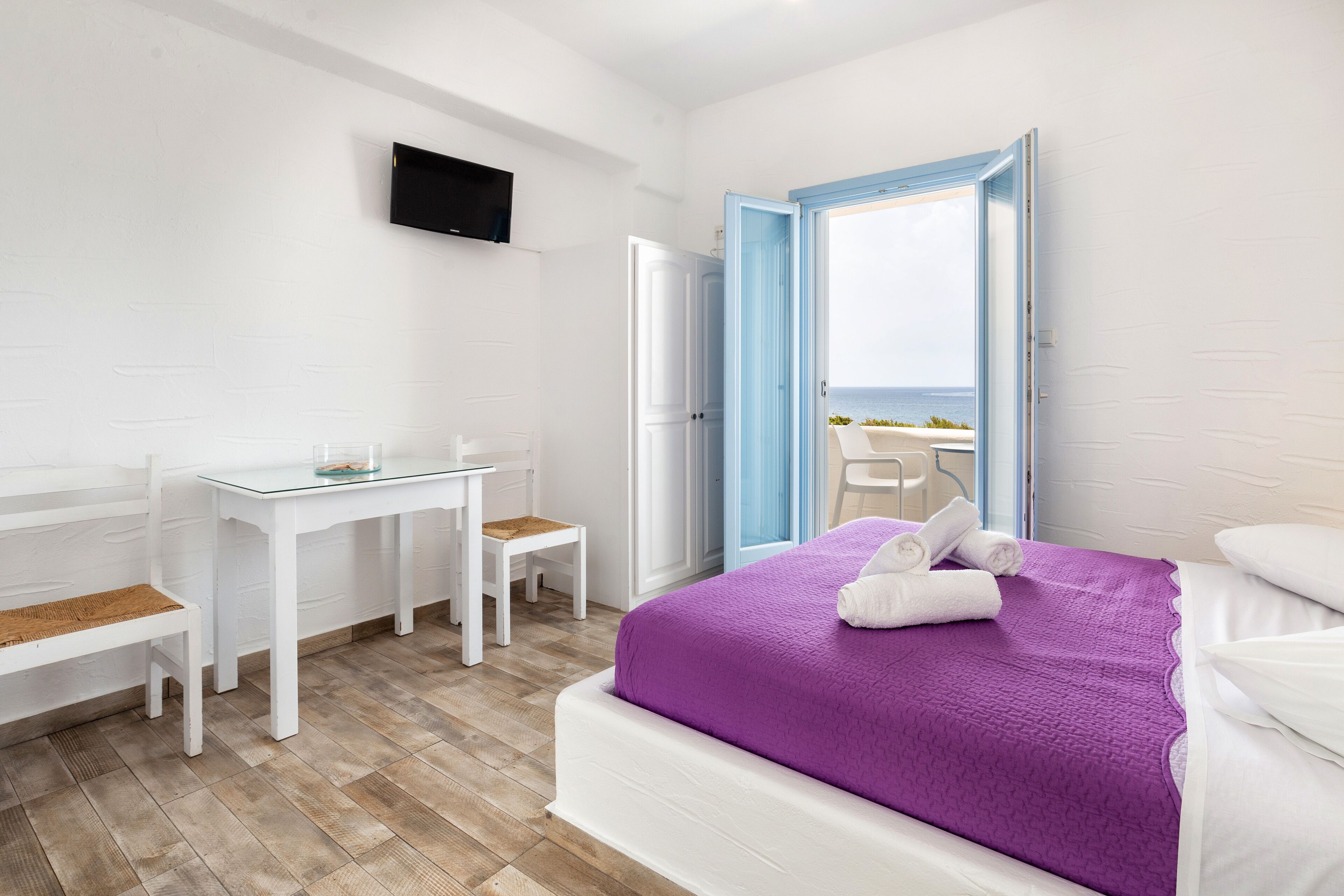 A bedroom with a bed, a desk, a chair, and a TV.