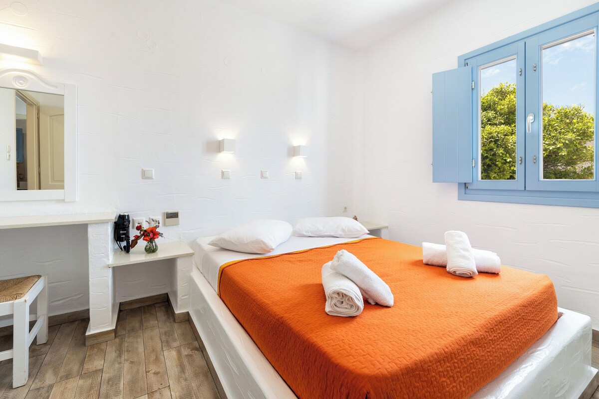 A room with a bed, a desk, and a window.