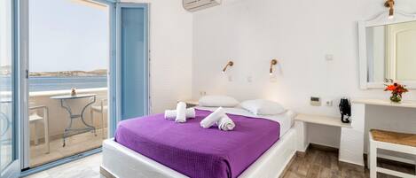 Ein Schlafzimmer mit Bett, Schreibtisch, Stuhl, Spiegel und Meerblick.